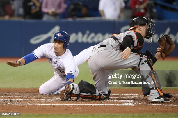 Darwin Barney of the Toronto Blue Jays slides across home plate to score the game-winning run on an RBI single by Richard Urena in the ninth inning...