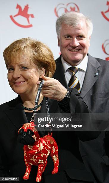 German Chancellor Angela Merkel holds a handbad shaped lika a dog as she inspects toys nominated for the Toy Innovation Arward 2009 together with...