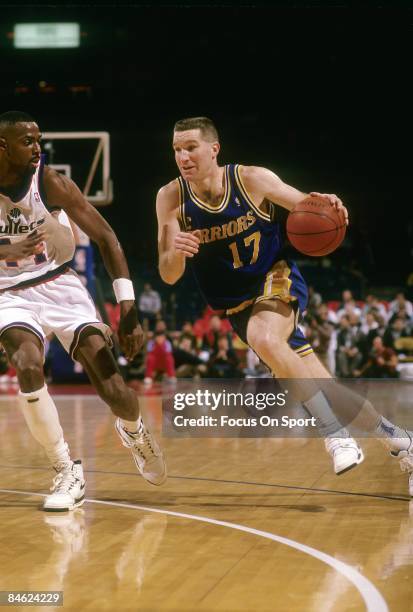 S: Chris Mullins of the Golden State Warriors attempts to get pass the defense of A.J. English of the Washington Bullets during a early circa 1990's...