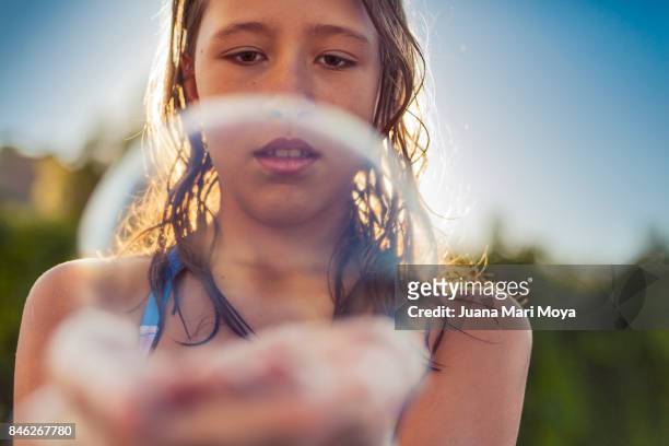 girl of blond hair plays with a bubble on his hand - niñez stock-fotos und bilder