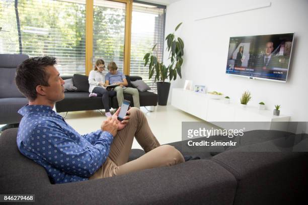 man watching tv - tv phone tablet stock pictures, royalty-free photos & images