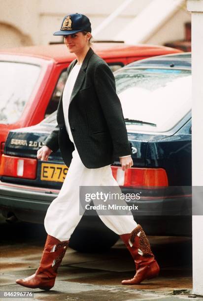 Princess Diana wearing an unusual combination of white trousers, boots, a blazer jacket and a baseball cap after taking her sons to school at...