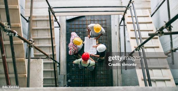 mujer arquitecto explicando detalles del plan al administrador del sitio y del capataz de pie en la parte inferior de la escalera de andamio - gestor de proyectos fotografías e imágenes de stock