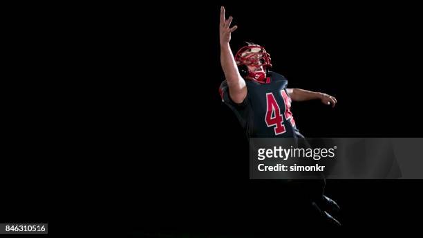 american football speler vangen van de bal in de lucht met een hand op zwarte achtergrond "n - ball and hand in the air stockfoto's en -beelden