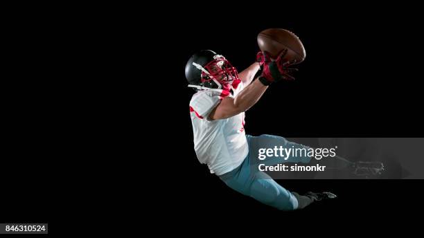 american football speler in de witte trui vangen van de bal in de lucht met een hand op zwarte achtergrond "n - ball and hand in the air stockfoto's en -beelden