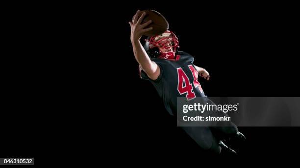 american football player jumping into the air and catching a ball while airborne - american football player catch stock pictures, royalty-free photos & images