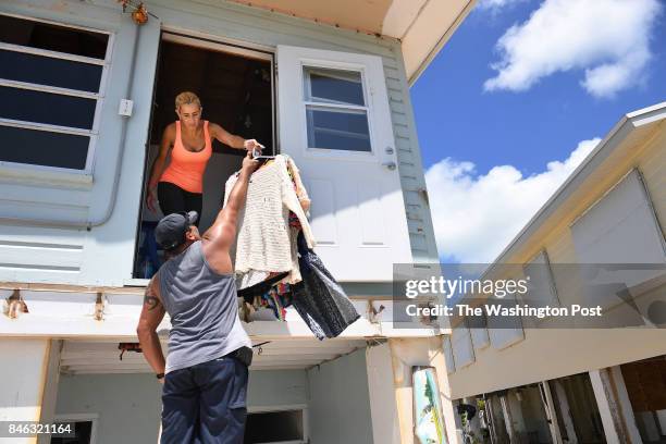 Ely Chavez hands clothes to her husband Kevin Chavez as they salvage belongings from their damaged home following Hurricane Irma in the Tavernier...