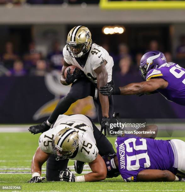 New Orleans Saints running back Alvin Kamara has to leap over offensive guard Andrus Peat to avoid the tackle of Minnesota Vikings defensive tackle...
