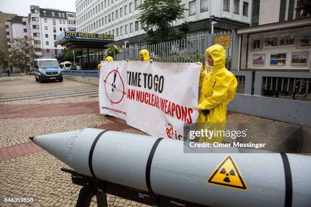 International campaign to abolish Nuclear Weapons activists wearing yellow hazard suits are seen next to a Styrofoam effigy of a nuclear bomb after...