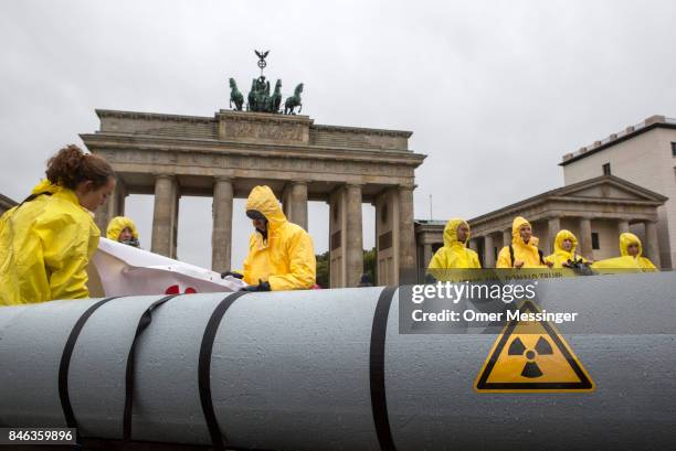 International campaign to abolish Nuclear Weapons activists wearing yellow hazard suits are seen next to a Styrofoam effigy of a nuclear bomb after...