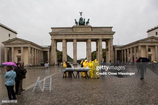 International campaign to abolish Nuclear Weapons activists wearing yellow hazard suits are seen next to a Styrofoam effigy of a nuclear bomb after...