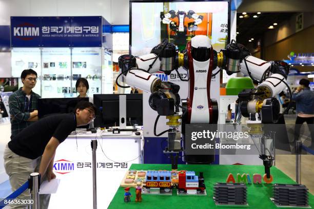 An employee looks at the Amiro robot developed by the Korea Institute of Machinery & Materials on display at the RobotWorld 2017 industry show in...