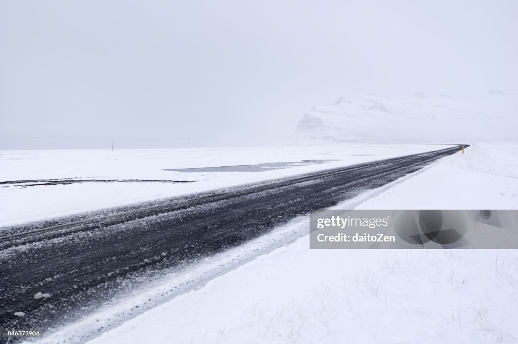 Hringvegur Ring Road in Iceland covered by ice and snow leading through winter landscape near Höfn, Southeast Iceland, Europe