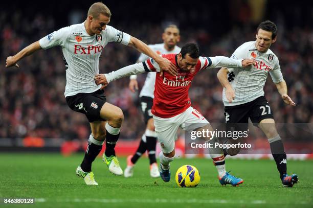 Santi Cazorla of Arsenal with Brede Hangeland and Sascha Riether both of Fulham in action during the Barclays Premier League match between Arsenal...