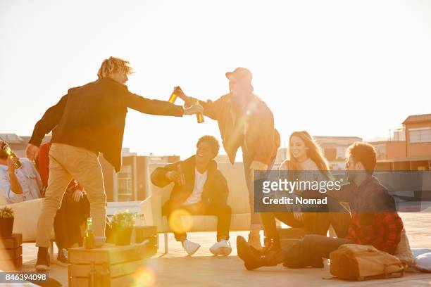 friends enjoying beer on terrace during summer - rooftop party stock pictures, royalty-free photos & images