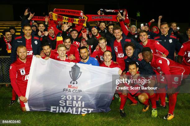 Adelaide United pose with the Westfield FFA Cup semi final qualification flag and their supporters in the crowd after winning the FFA Cup Quarter...