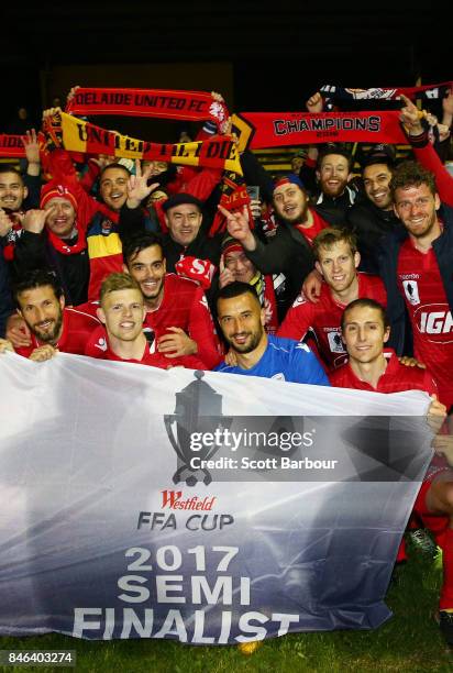 Adelaide United pose with the Westfield FFA Cup semi final qualification flag and their supporters in the crowd after winning the FFA Cup Quarter...