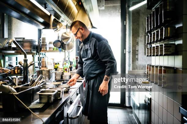 head chef cooking on hob in well stocked restaurant kitchen - stove top stock pictures, royalty-free photos & images