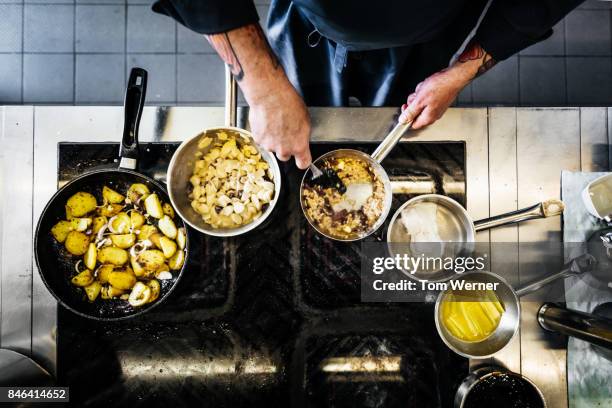 aerial shot of chef cooking on the hob in restaurant kitchen - kochgeschirr stock-fotos und bilder