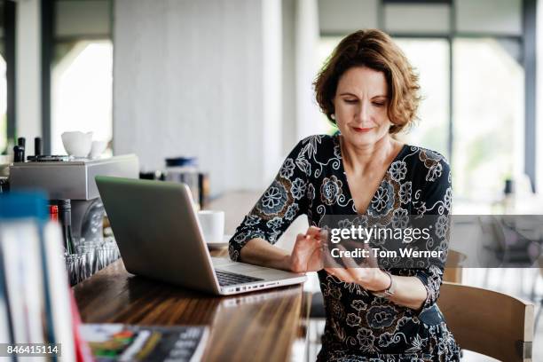 businesswoman using smartphone while sitting at restaurant bar - frau mittellanges haar brünett stock-fotos und bilder