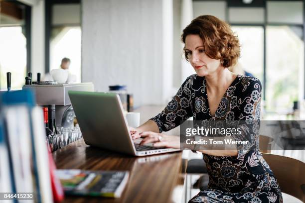 businesswoman sitting at restaurant bar, working over lunch - geschäftsfrau kleid stock-fotos und bilder