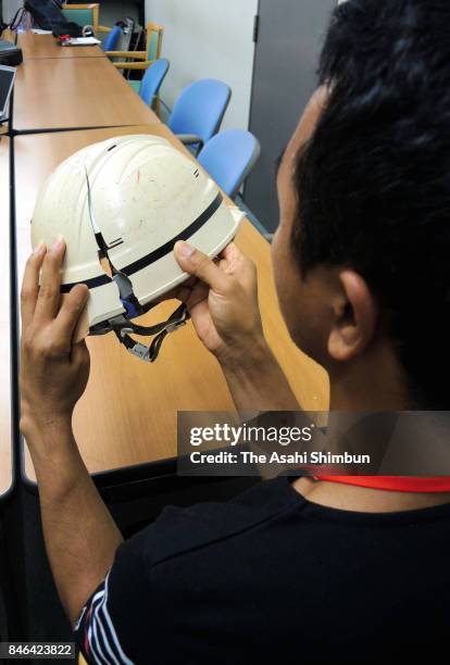 The Cambodian man, who developed depression due to his working conditions, shows a damaged helmet that he used at work on September 12, 2017 in...