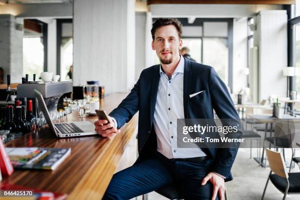 portrait of businessman sitting at restaurant bar using smartphone - bar berlin stock pictures, royalty-free photos & images