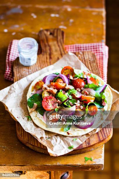 homemade wheat flat bread with fresh chard leaves, roasted cherry tomatoes, red onion and crispy bacon with cream cheese sauce on a wooden cutting board for a snack for picnic, selective focus - cutting red onion stock pictures, royalty-free photos & images