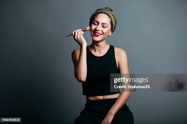 woman applying powdered makeup to her face with a brush - applying makeup with brush stock pictures, royalty-free photos & images
