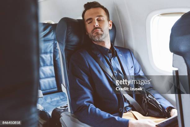 飛行機旅行中に眠っているビジネスマン - 飛行機の座席 ストックフォトと画像