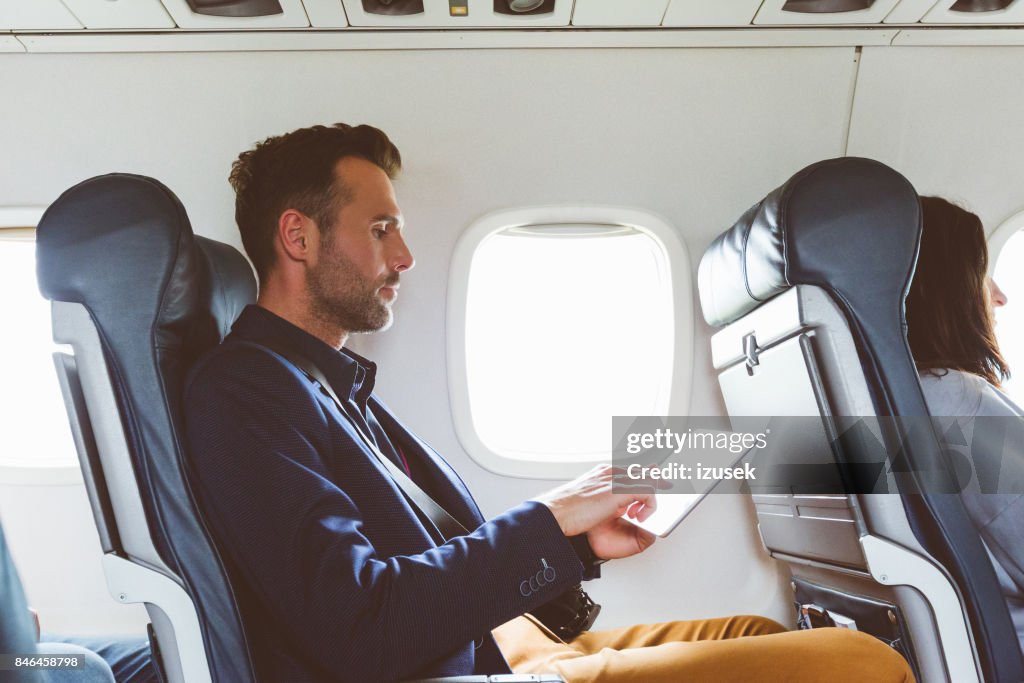 Empresario con tableta digital en avión