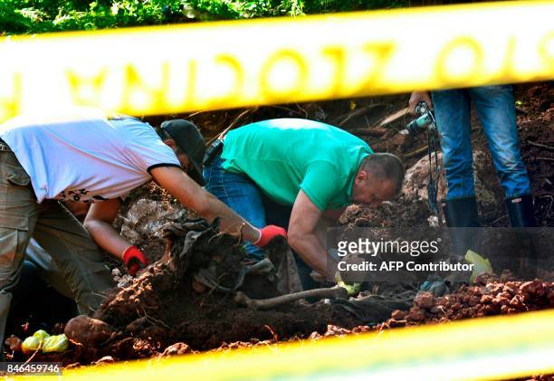 Members of a Bosnian forensic experts team and workers find human remains, at the site of a newly discovered mass grave in the village of Tugovo,...