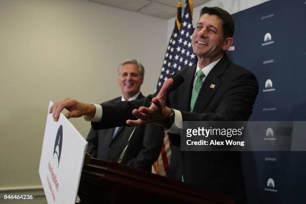 Speaker of the House Rep. Paul Ryan fixes a falling sign as House Majority Leader Rep. Kevin McCarthy looks on during a news briefing September 13,...