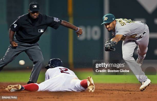 Boston Red Sox player Xander Bogaerts dives into second base with a very short third inning double, as the throw from the outfield gets by Oakland...