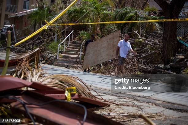 People carry plywood in front a damaged building after Hurricane Irma in St John, U.S. Virgin Islands, on Tuesday, Sept. 12, 2017. After being struck...