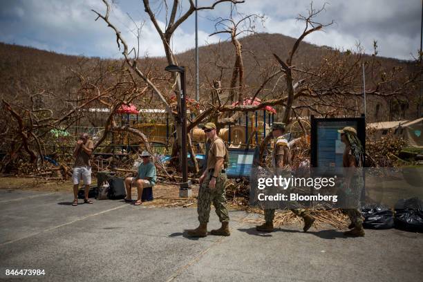 Members of the U.S. Military pass people waiting for transportation after Hurricane Irma in St John, U.S. Virgin Islands, on Tuesday, Sept. 12, 2017....