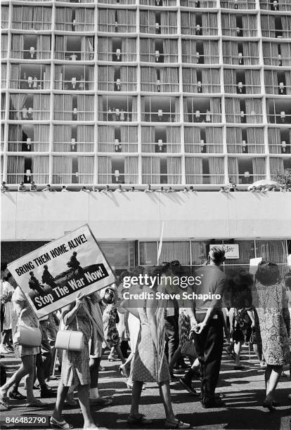 View of protestors during a anti-Vietnan war demonstration on Wilshire Boulevard, Los Angeles, California, 1969. One woman carries a sign that reads...