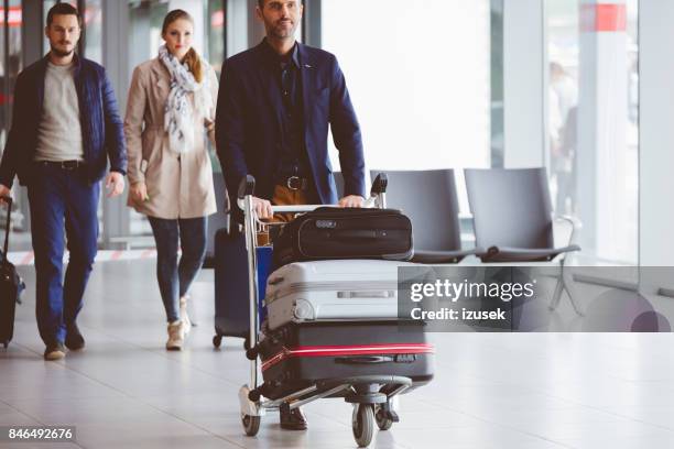 personas caminando en el aeropuerto con equipaje - carrito-para-equipaje fotografías e imágenes de stock