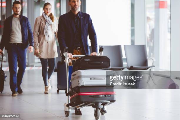 mensen lopen in de luchthaventerminal met bagage - luggage trolley stockfoto's en -beelden