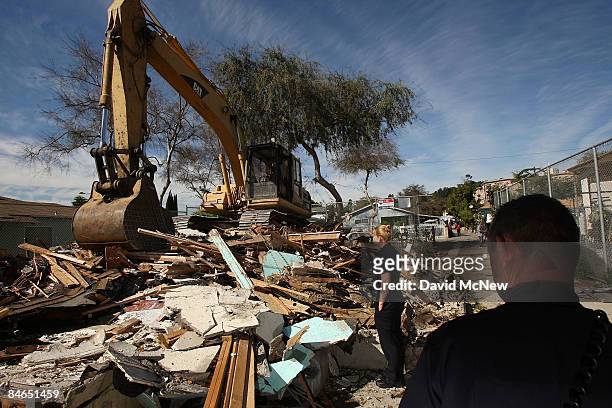 Los Angeles Police officers look on the scene where a demolition crew is tearing down a rented house that city officials say was used as the...