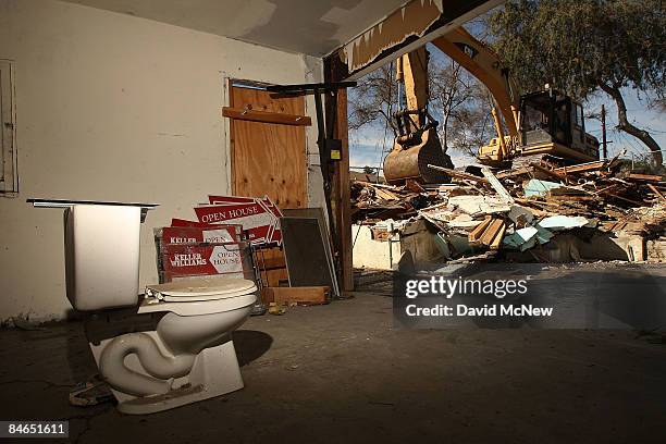Toilet and realtor open house signs stand in the garage as a demolition crew tears down a rented house that city officials say was used as the...