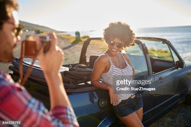 junger mann, die aufnahme von bildern ihrer freundin bedeutung roadtrip - interracial wife photos stock-fotos und bilder