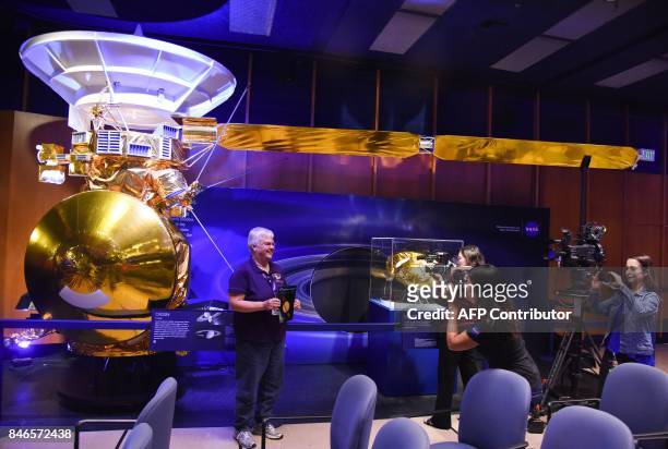 People pose in front of a 1/2 scale model of the Cassini spacecraft at a news briefing for the end of the Cassini mission to Saturn, September 13,...