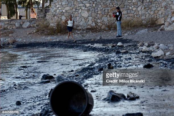 People inspect a beach on the coast of Salamis Island which has been polluted with oil on September 13, 2017 in Salamis, Greece. The small tanker...