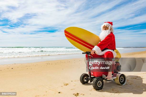 santa claus riding a motorised esky cooler on the beach - santa stock pictures, royalty-free photos & images