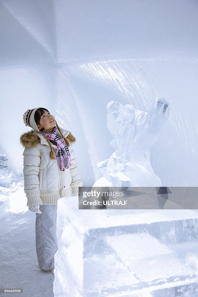 A girl is looking at the wall of ice.