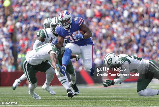 Mike Tolbert of the Buffalo Bills runs with the ball during NFL game action as he breaks a tackle from Julian Stanford of the New York Jets and...