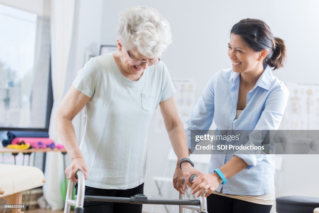 Healthcare professional helps senior woman walk with a walker