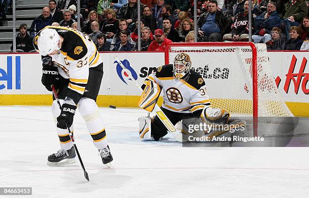 Tim Thomas of the Boston Bruins focuses on the puck as a shot gets though the legs of teammate Zdeno Chara in a game against the Ottawa Senators at...