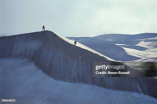 two sandboraders ride the dunes after snowstorm - great sand dunes national park stock-fotos und bilder